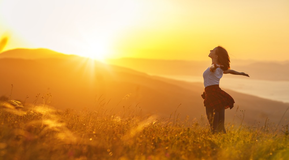 Woman embracing sunset in nature, symbolizing recovery quotes