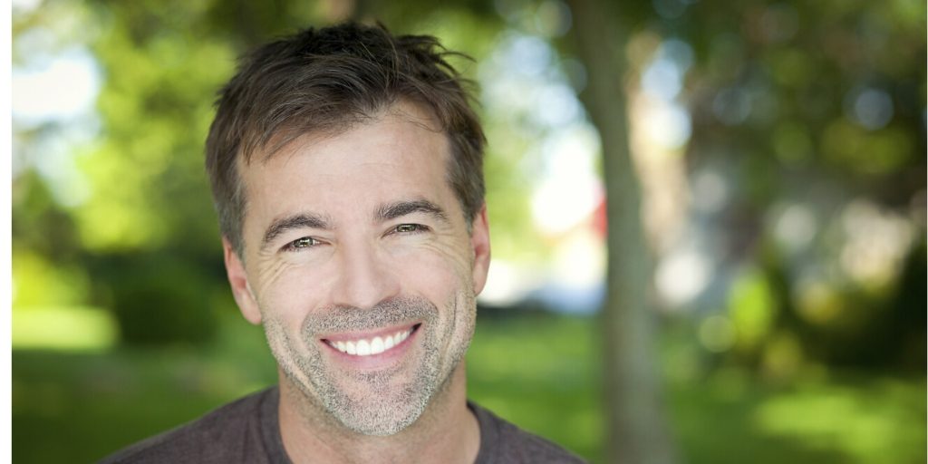 Smiling man in a park, symbolizing hope and success in Rehab Reading.