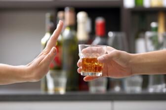 Hand refusing a glass of whiskey, symbolizing alcohol recovery