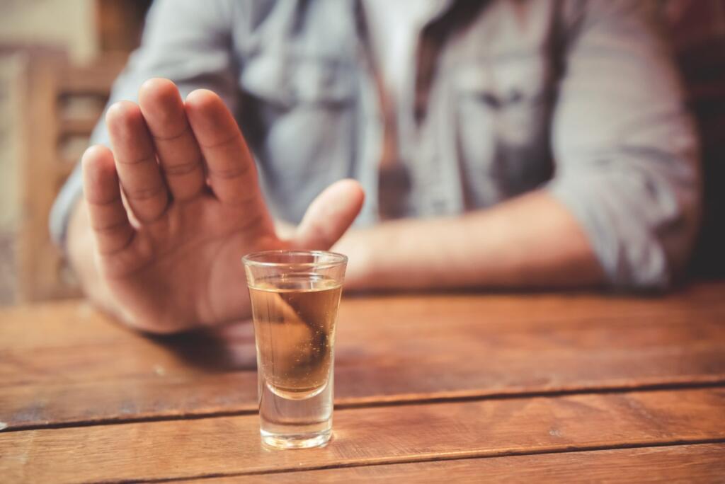 Person rejecting alcohol shot for addiction recovery support