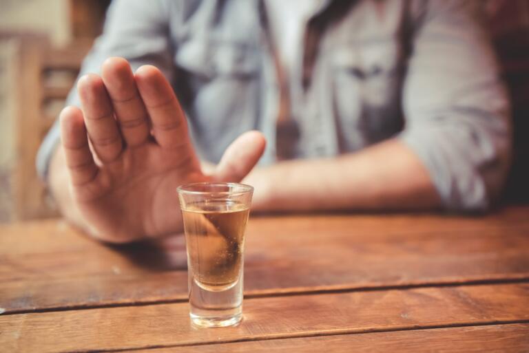 Person rejecting alcohol shot for addiction recovery support