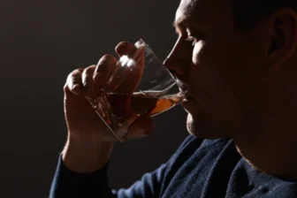 Profile of a person secretly drinking alcohol in dim light
