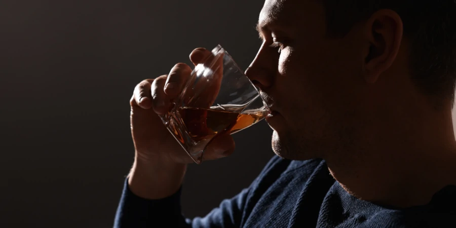 Profile of a person secretly drinking alcohol in dim light