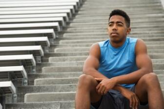 Young man sitting on stairs, reflecting on the side effects of steroids