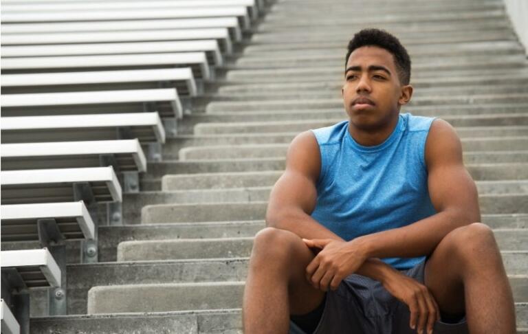 Young man sitting on stairs, reflecting on the side effects of steroids