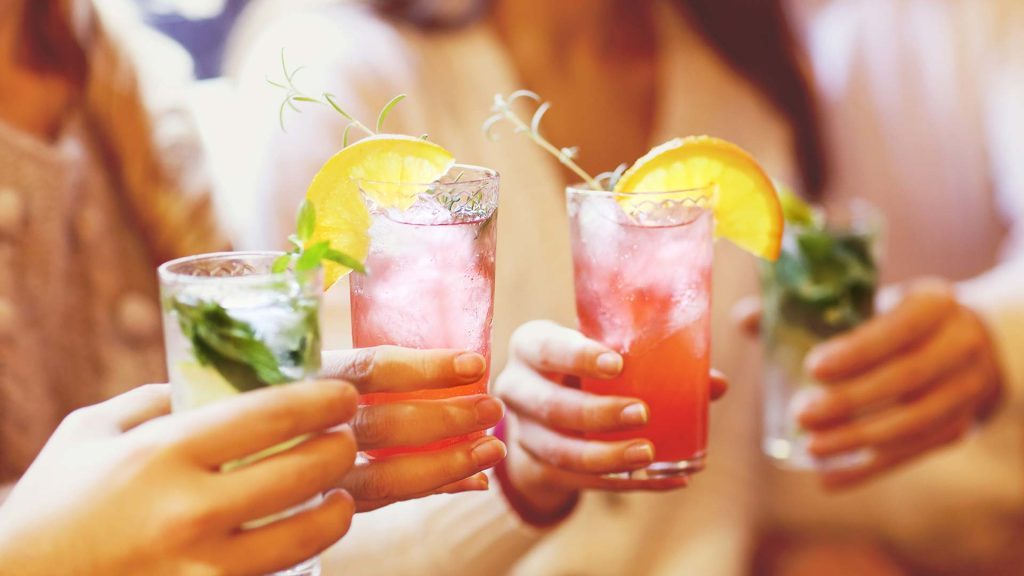 Hands holding alcohol-free drinks to celebrate sober for October