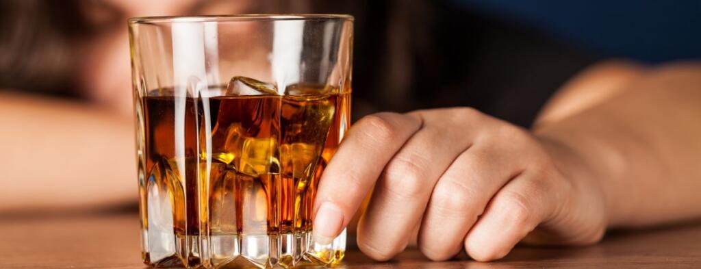 Close-up of a hand holding a glass of whiskey, symbolizing alcohol recovery