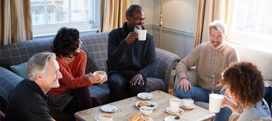 Diverse group discussing alcohol recovery with coffee in cozy setting