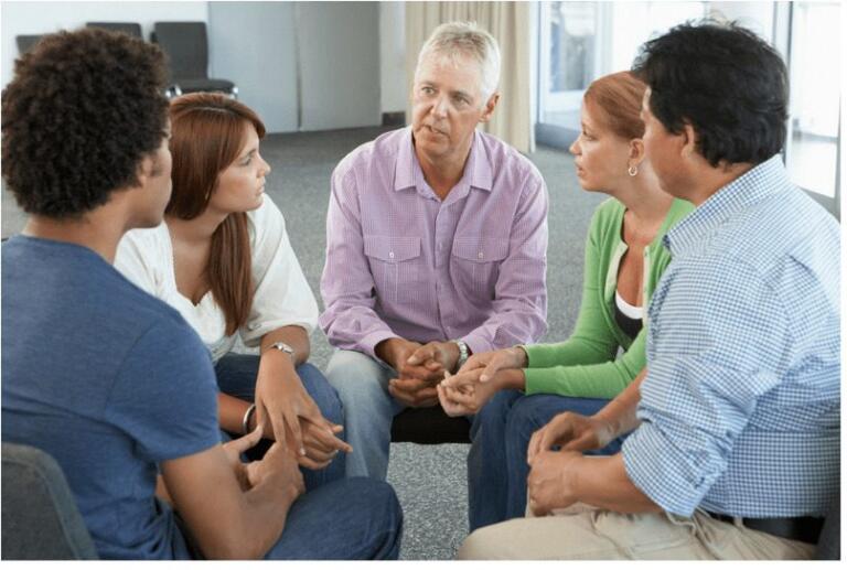 Diverse group in a support session discussing alcohol recovery.