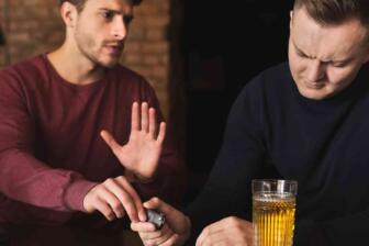 Two men discussing help for alcoholic friend at bar