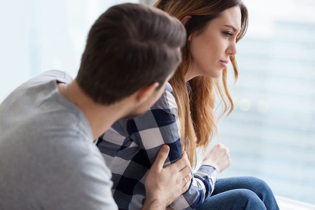 Man comforting a woman during alcohol recovery discussion
