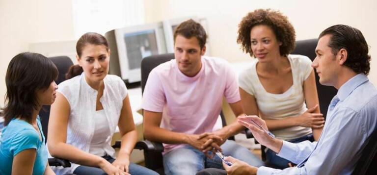 A diverse group discusses alcohol recovery in a supportive setting.