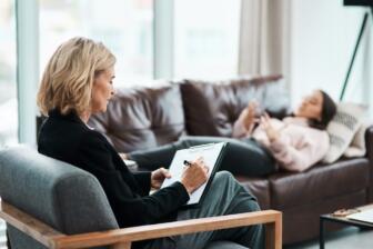 Therapist taking notes during a counseling session for alcohol recovery.