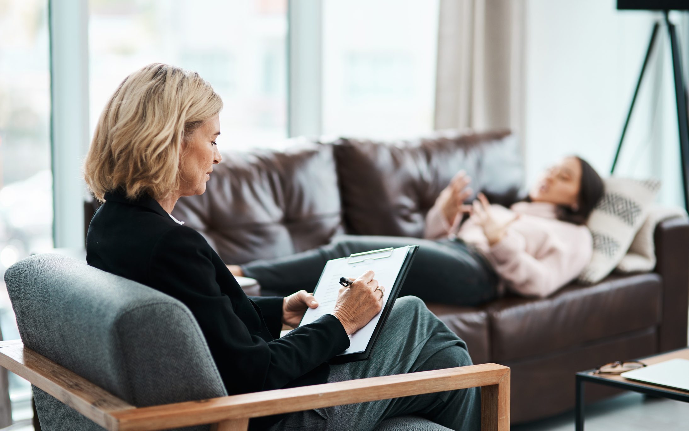 Therapist taking notes during a counseling session for alcohol recovery.