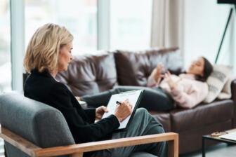 Therapist counseling a woman on a sofa about alcohol addiction recovery.
