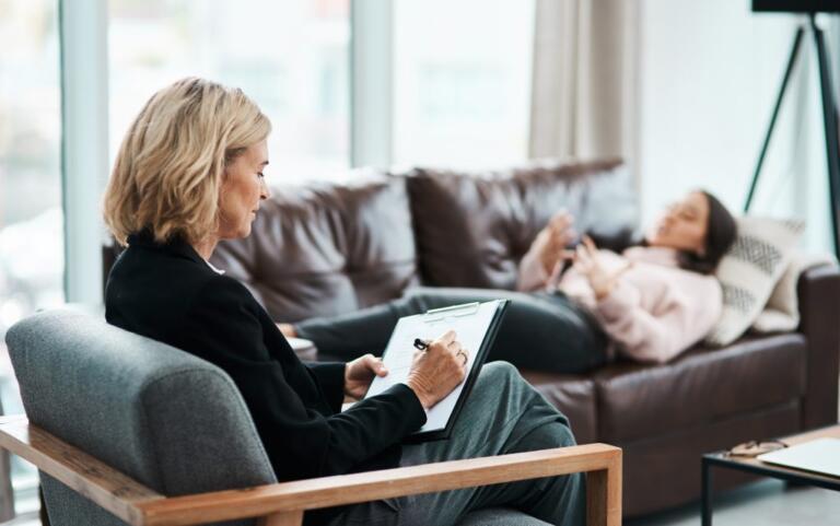 Therapist counseling a woman on a sofa about alcohol addiction recovery.