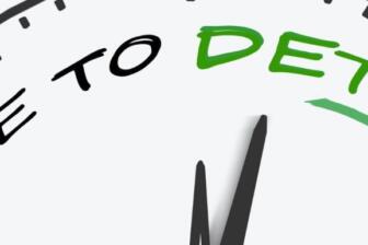 Hand writing "Time to Detox" on clock face, symbolizing alcohol recovery