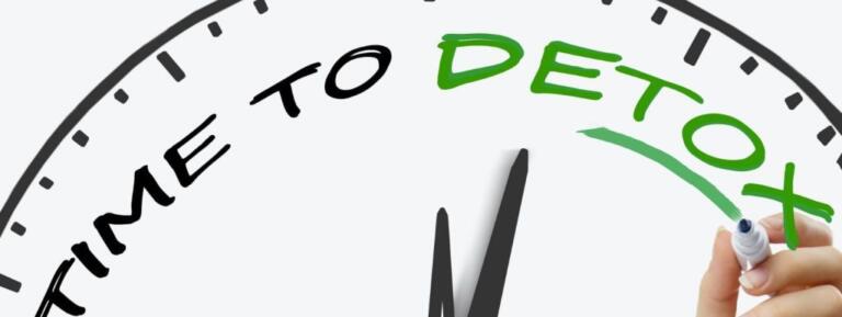Hand writing "Time to Detox" on clock face, symbolizing alcohol recovery