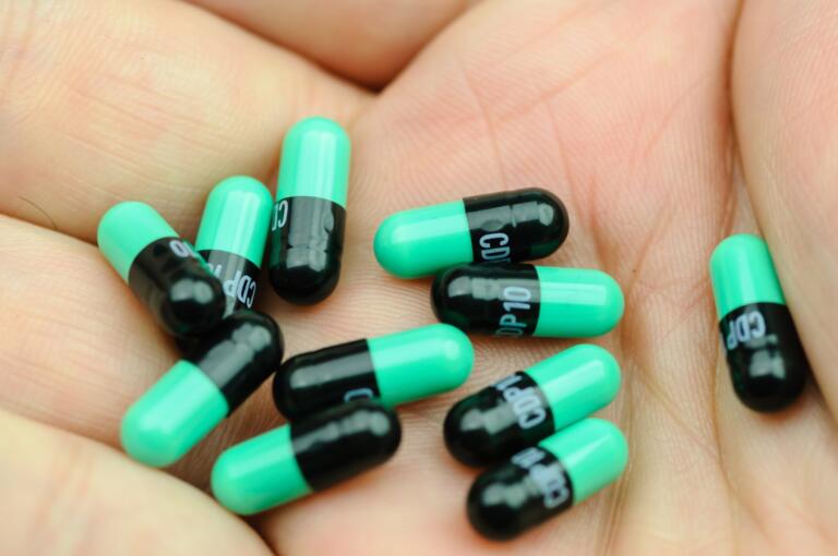 Hand holding green and black pills, symbolizing Valium withdrawals