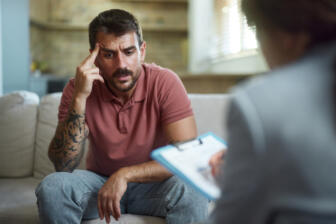 Man sitting on a couch talking about alcoholism with a rehab counsellor