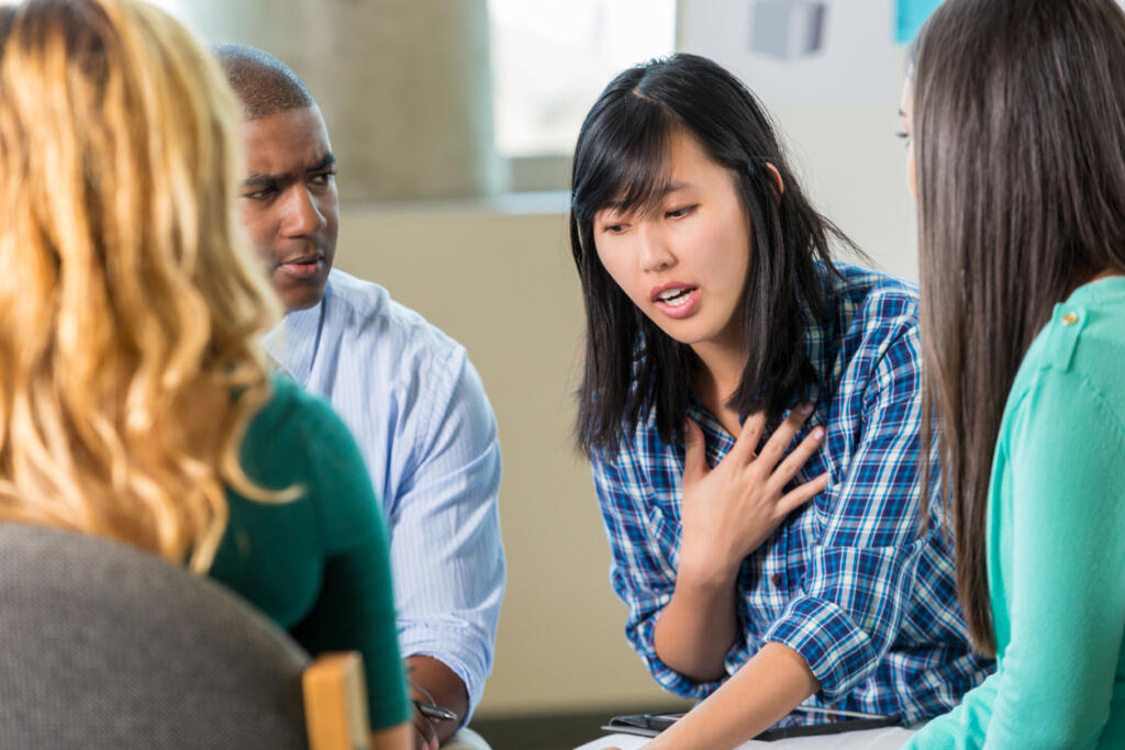Woman sharing with a diverse group in CBT rehab therapy