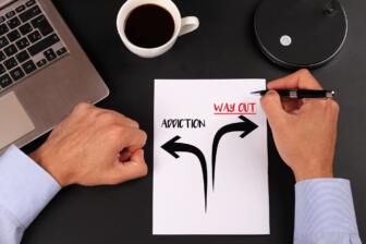 Person drawing arrows on paper representing addiction and recovery path