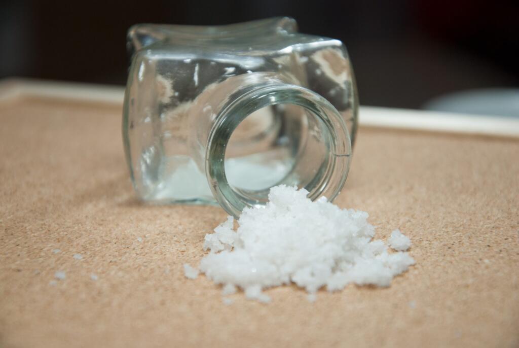 Spilled salt from overturned container on table