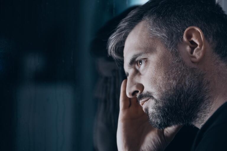 Man contemplating alcohol rehab by a window