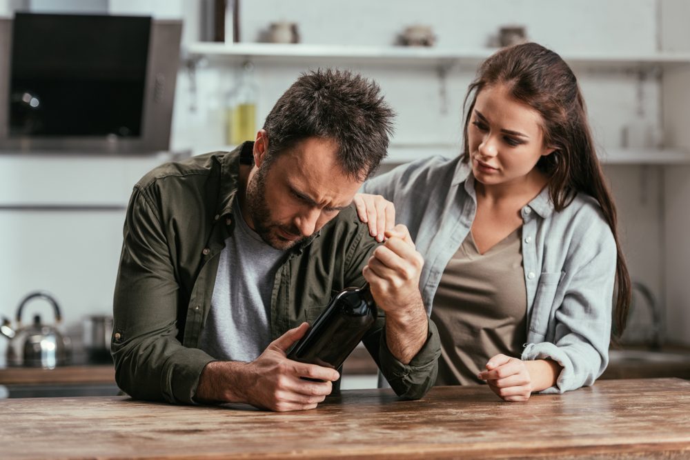 A supportive partner helps a man struggling with alcohol rehab